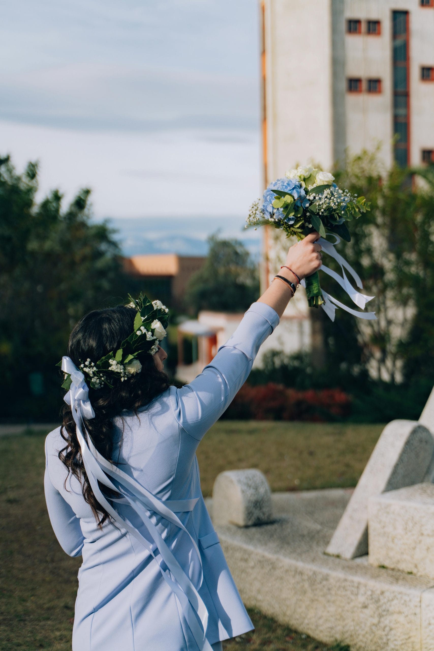 A woman in a floral crown raises a bouquet during graduation in Chieti, Italy.